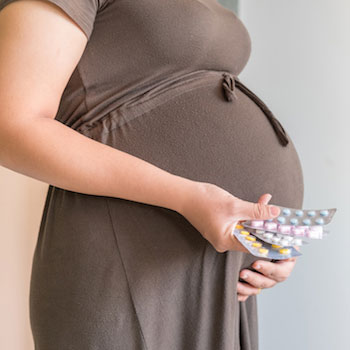 Pregnant woman holding supplements